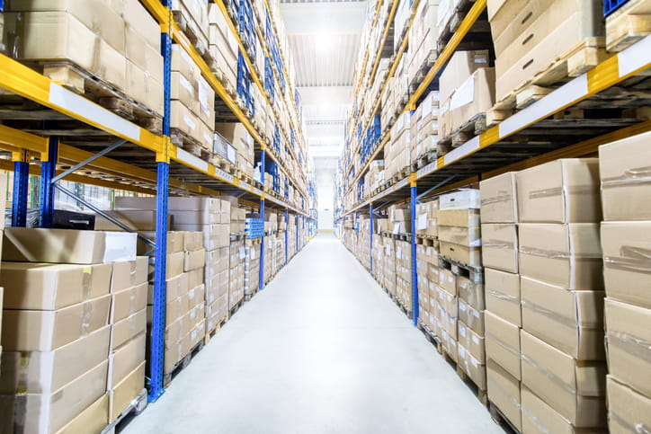 A hallway in a bright warehouse with lots of boxes display neatly on the shelves