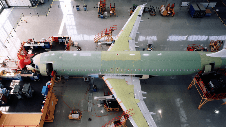 An airplane parked in a garage with maintenance staff working