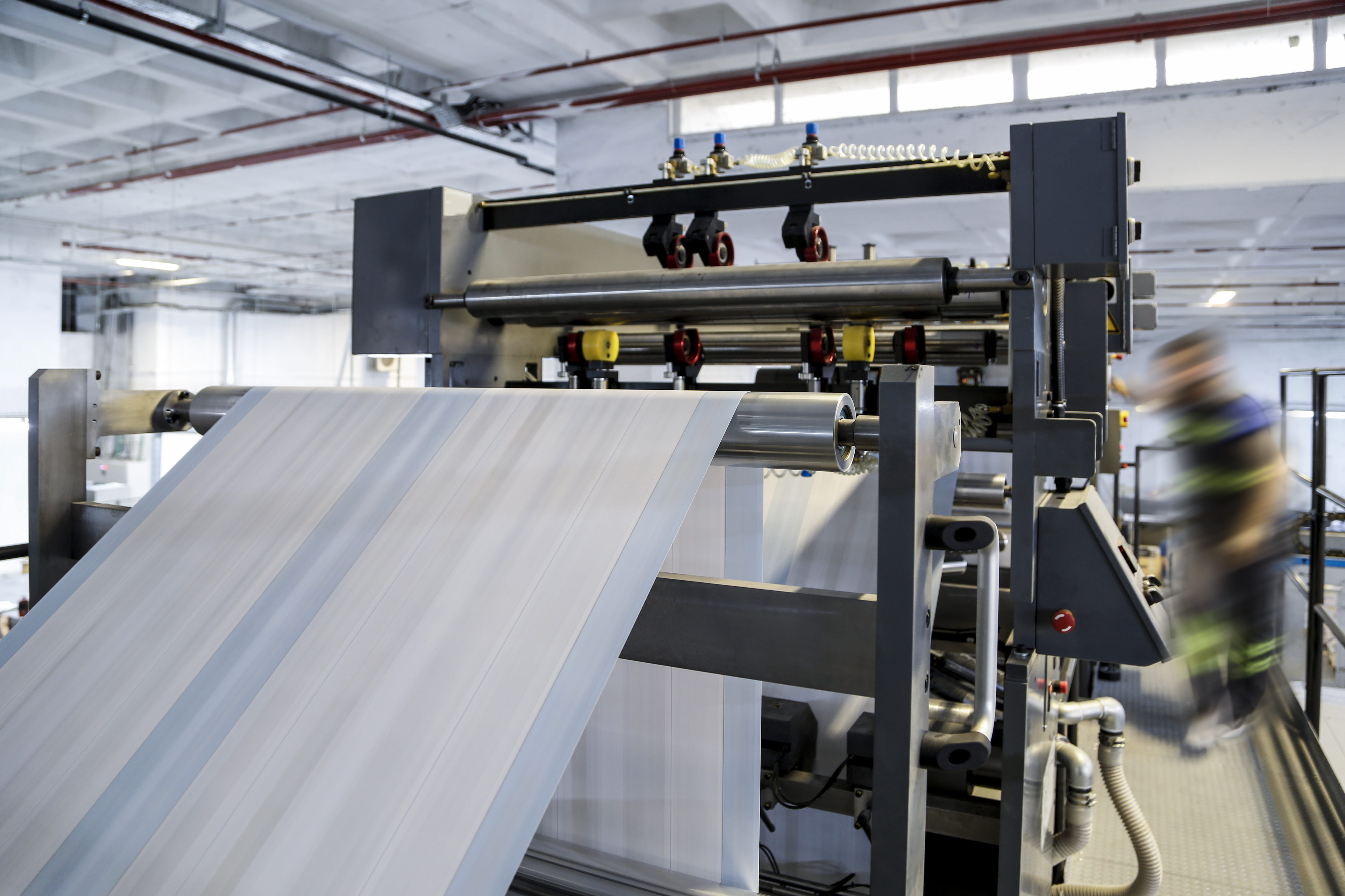 A textile machine knitting a piece of white cloth