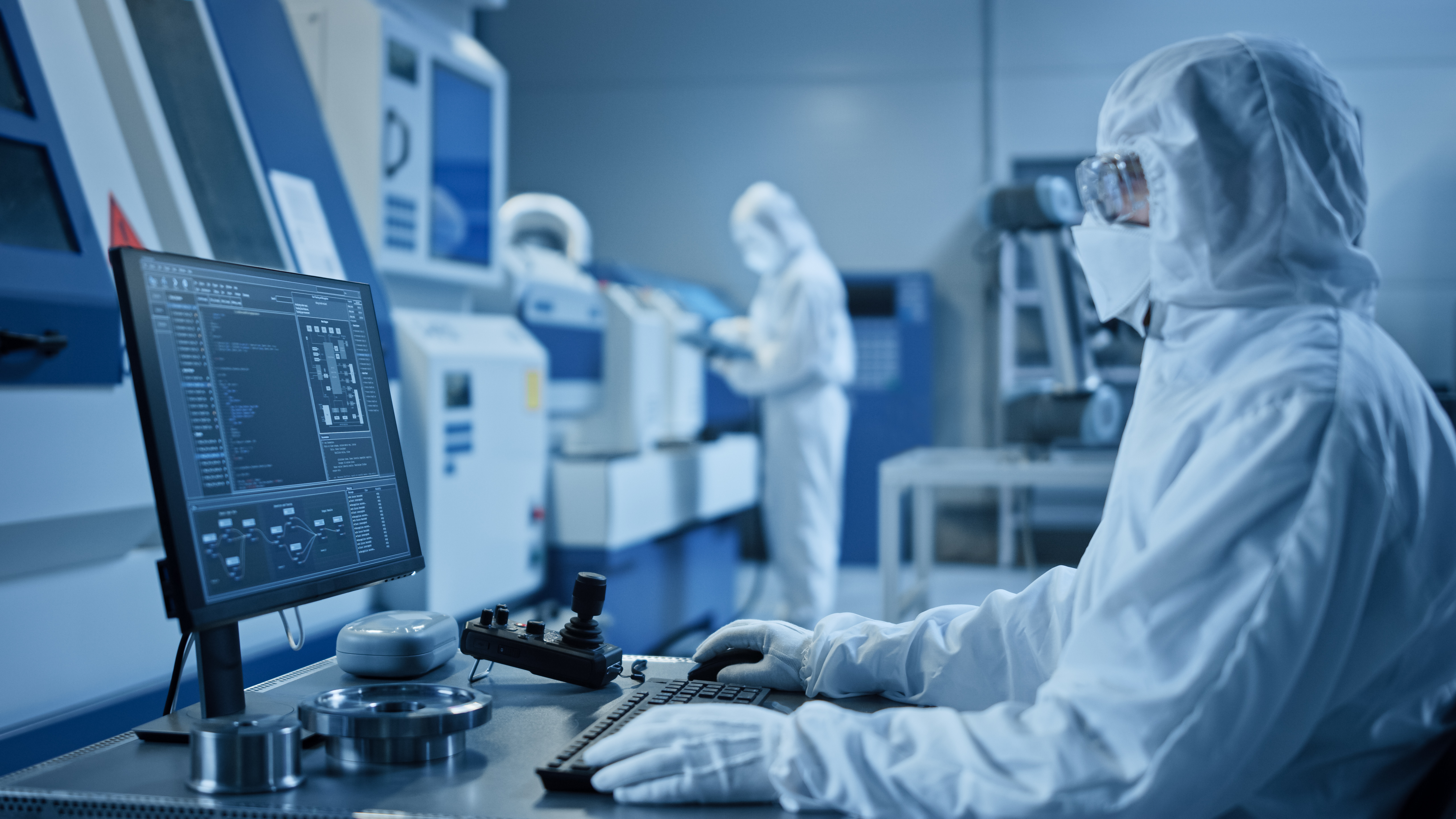 A medical professional wearing in a full set of personal protective equipment working in front of a computer in a lab