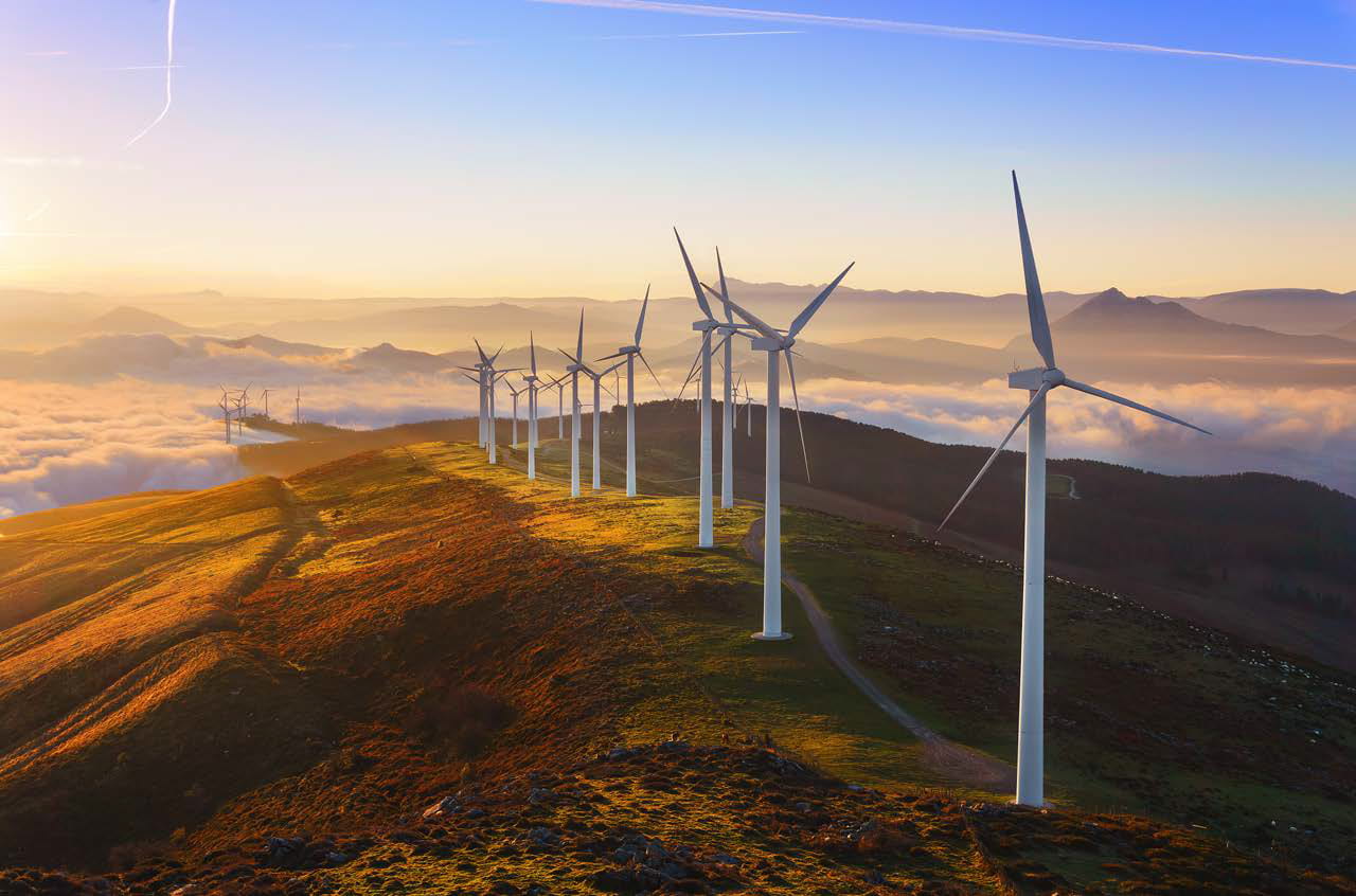 White wind turbines lined up on a hill