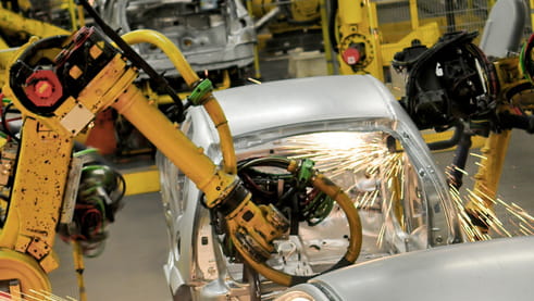 A machine cutting a white metal object with sparkles