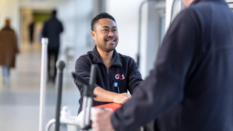 Two cleaning staff members chatting in a modern building hallway.