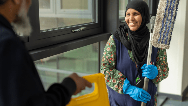 A cleaning lady smiling and holding a mop