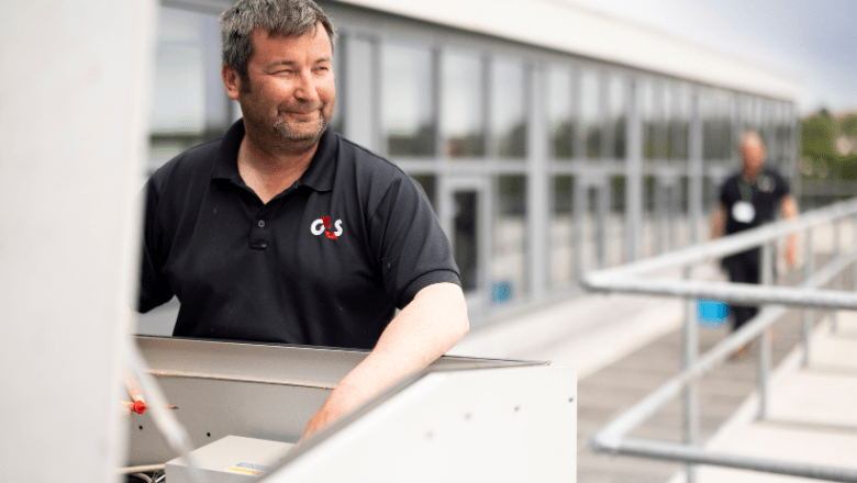 Maintenance professional in a G4S uniform repairing a machine