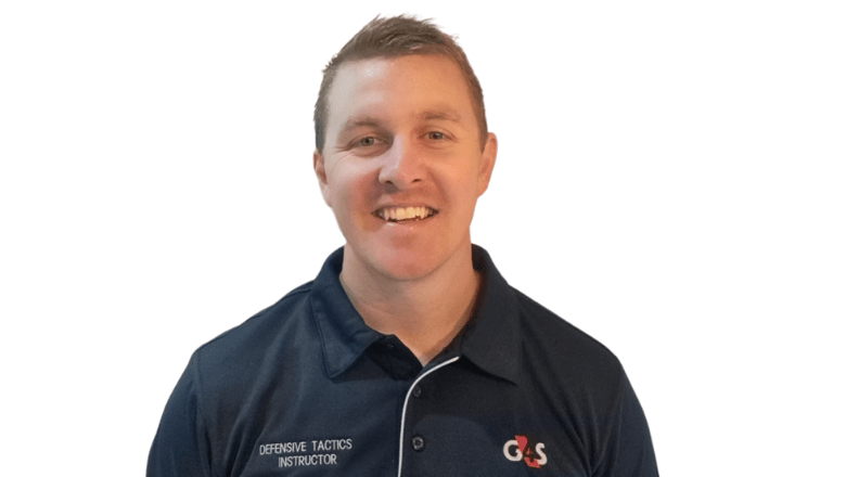 A G4S Defensive Tactics Instructor in a blue polo shirt looks at the camera smiling