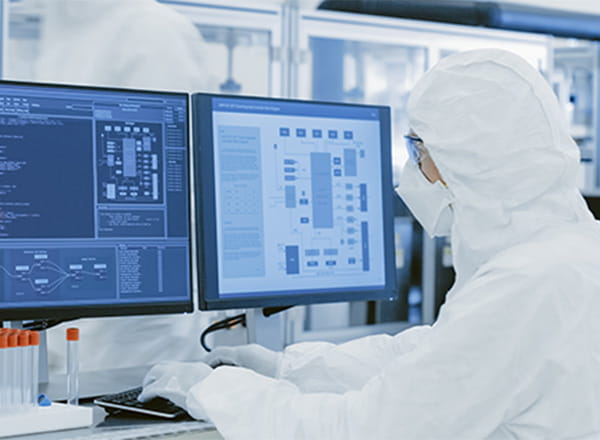 Person med hvid dragt på der sidder ved computer