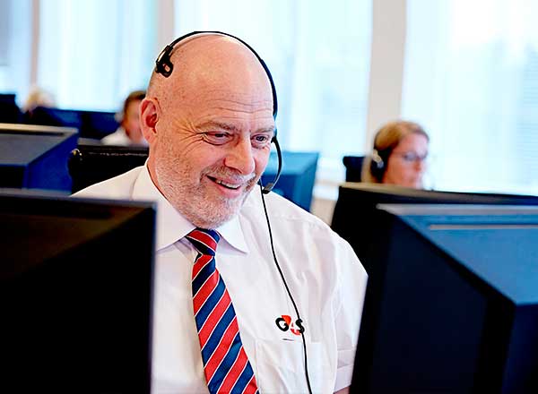 Vagtassistent på kontrolcentralen smiler til kunden i røret