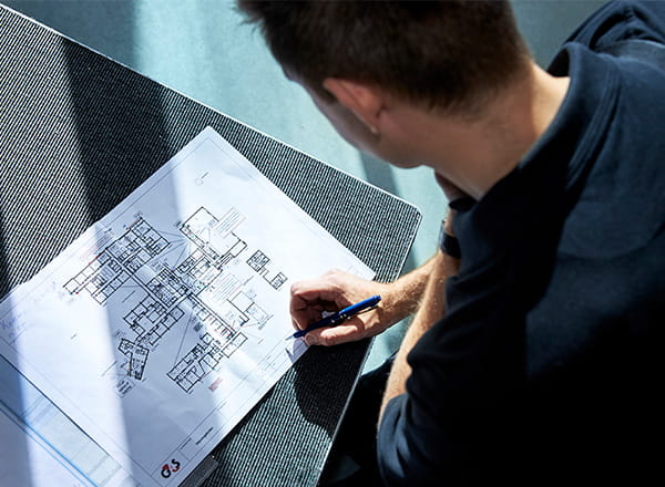 Montør der kigger og skriver på tegning over bygning