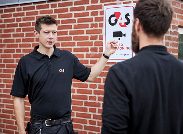 Montør peger på videovervågningskilt 