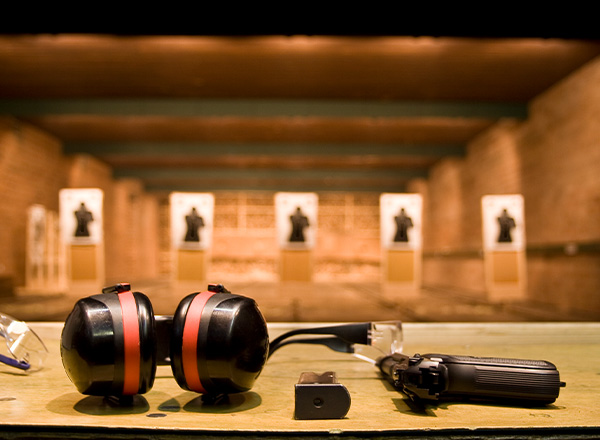 Pistol og høretelefoner der ligger ved skydebane