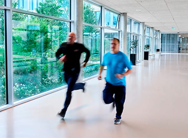 Sikkerhedsmedarbejder løber på gang med anden medarbejder