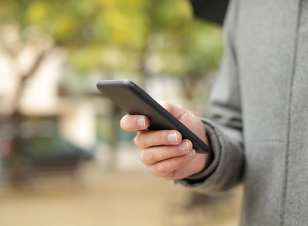 Person udenfor med telefon i hånd