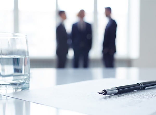 Vandglas på bord sammen med kuglepen i mødelokale