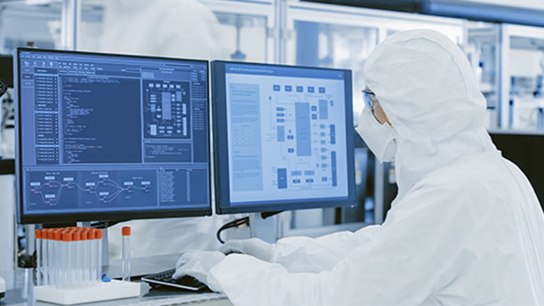 Person der sidder ved computer med prøver i reagensglas