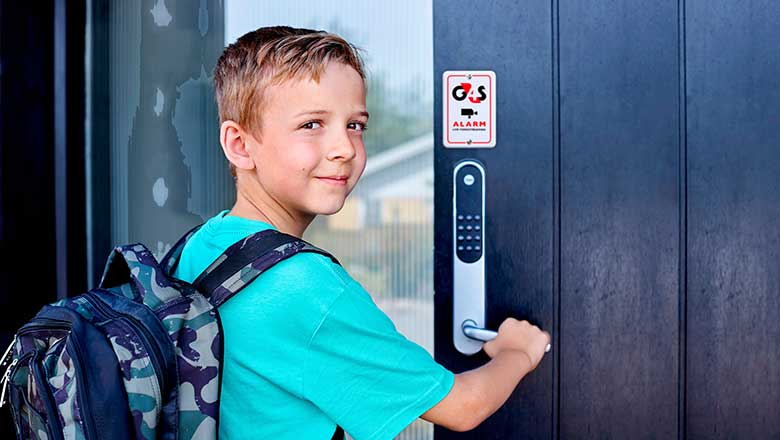 Dreng står med skoletaske på og slår alarmen fra