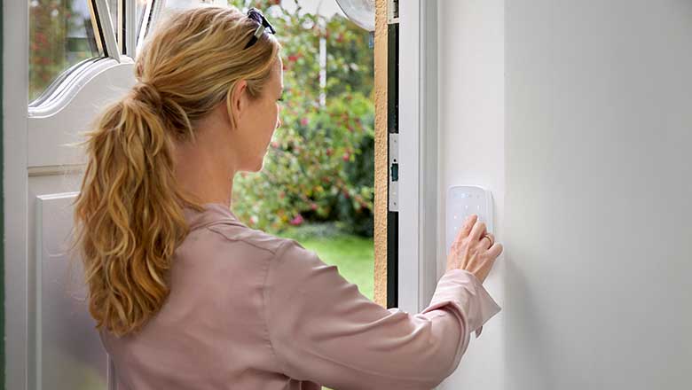 Kvinde betjener alarmen på betjeningspanelet, da hun er på vej ud af døren