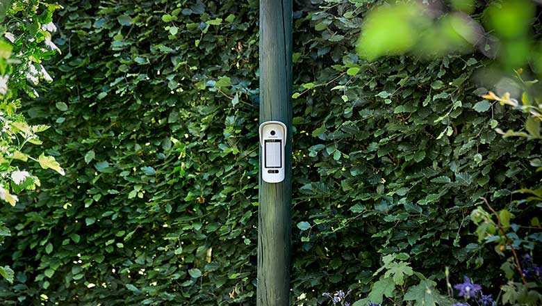 Udendørs kameradetektor hænger på en pæl i haven