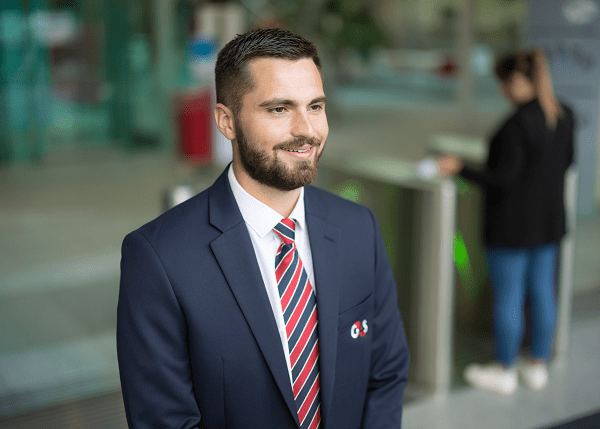 Male wearing G4S uniform standing in front of turn-styles