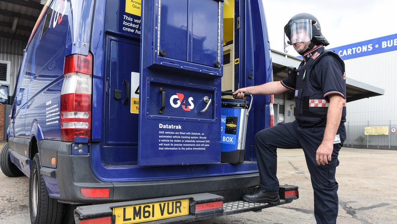 G4s employee wearing protective gear standing next to G4S van