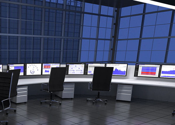 A monitor room with various monitors on a curved desk