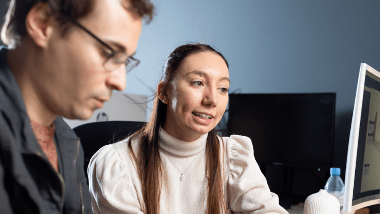 Two colleagues discussing in front of a monitor screen 