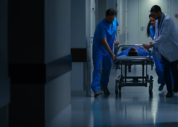 Hospital staff and doctors with a patient on a bed in the hallway