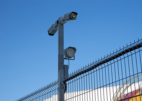 Outdoor CCTV near a fence under a blue sky