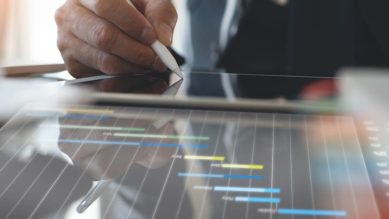 A hand holding a pen writing on a tablet