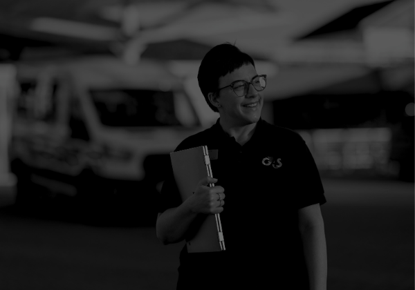Patient Transport Liaison Officer, with an ambulance by a hospital entrance, in the background.