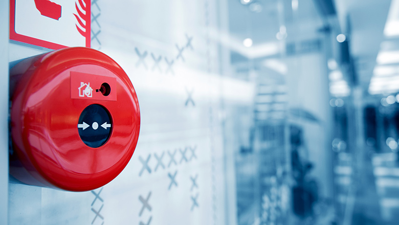 A red fire alarm on a white wall