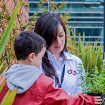 Female wearing a G4S light blue uniform holding a child wearing a red jacket