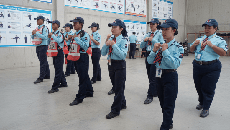  Group of female security guards in uniform attending a training session indoors.