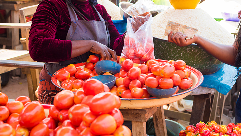 woman at market buying tomatoes with cash