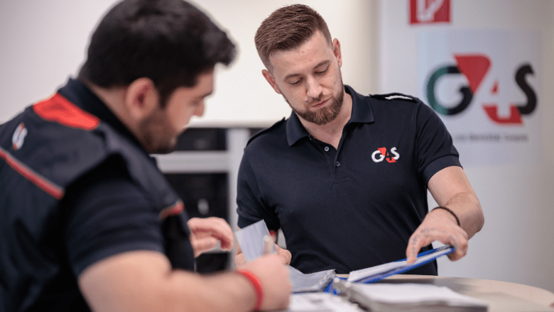 Divi darbinieki G4S fomas tētpos. Viens raksta dokumentus otrs lasa dokumentu.