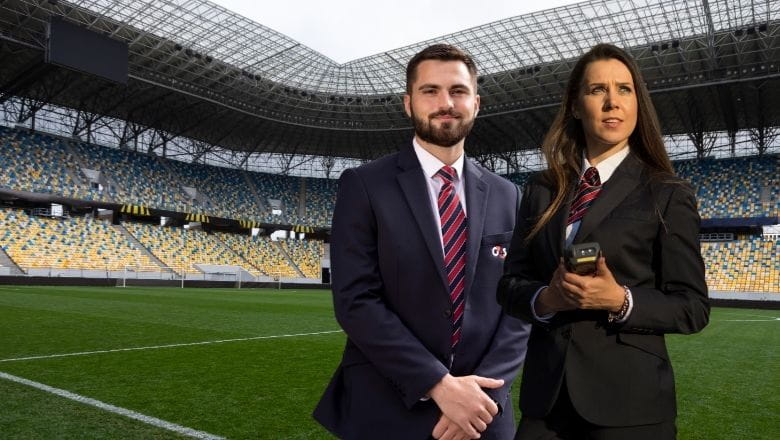 Vīrietis un sieviete G4S formas tērpā publiska pasākuma apsardzē. 